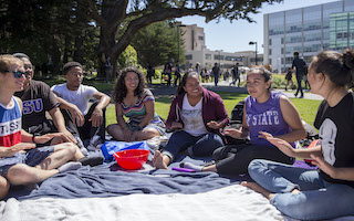 Students sitting in circle talking on campus grass